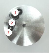 A circular metal object with white circles

Description automatically generated